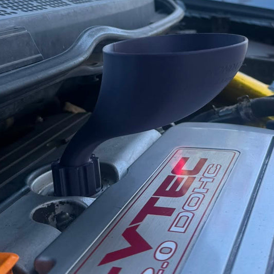 A close-up of a car engine bay, a civic si fa5 with the hood open, showing a threaded oil funnel inserted into engine valve cover. The silver engine cover has a red and white 'i-VTEC 2.0 DOHC'.